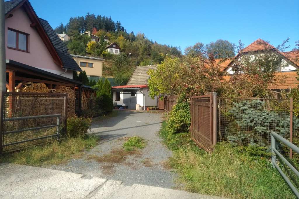 Otevřená brána a štěrková příjezdová cesta k brusírně z ulice Amerika